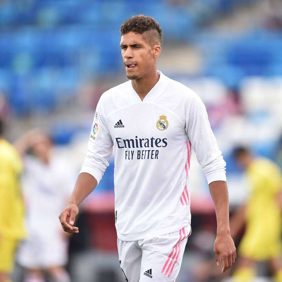 Fußballspieler in weißem Real Madrid-Trikot läuft während eines Spiels auf dem Feld. — Raphael varane Hintergrundbild
