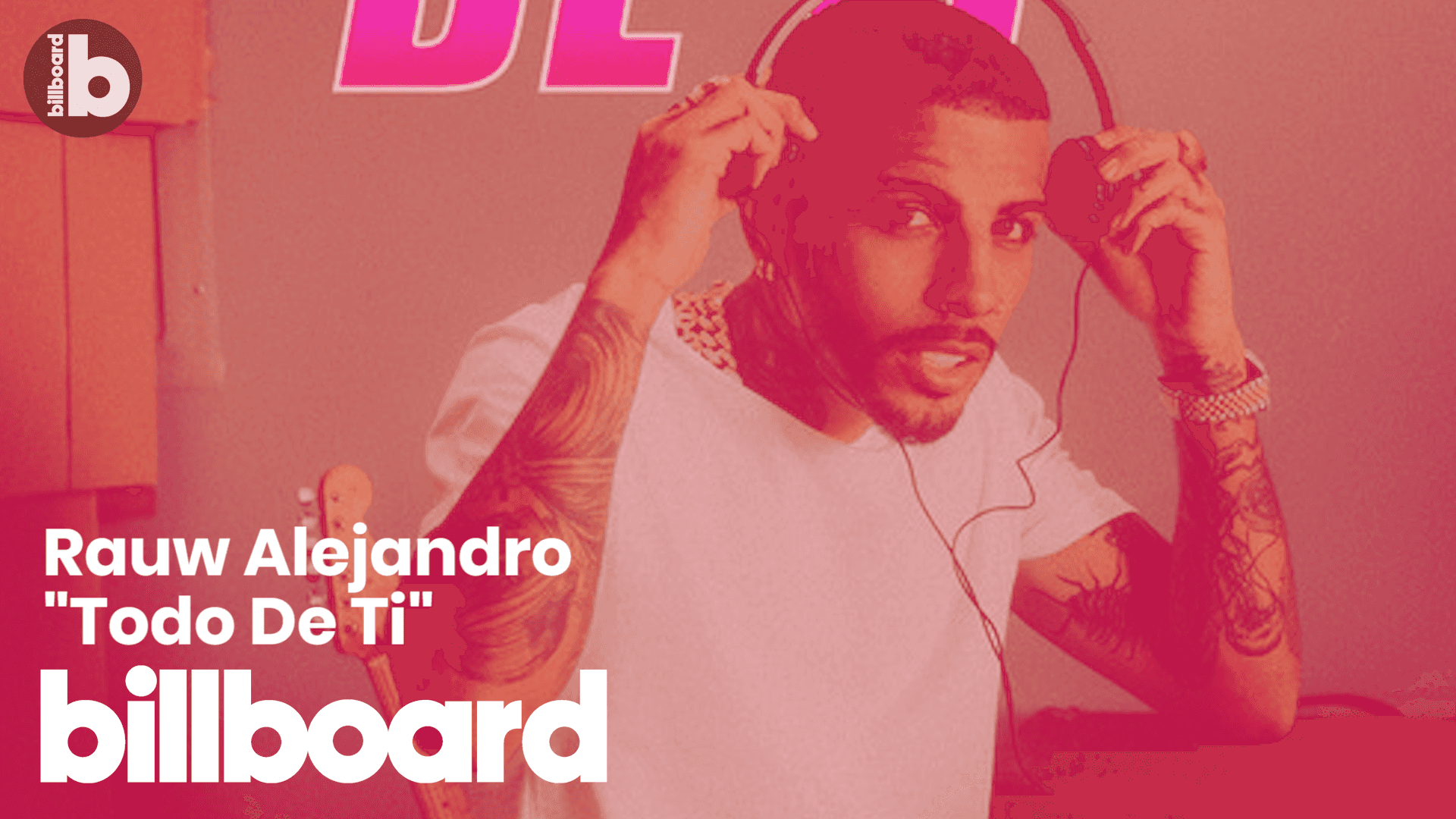 Man with tattoos adjusting headphones in a pink-toned studio setting. — Rauw Alejandro Background
