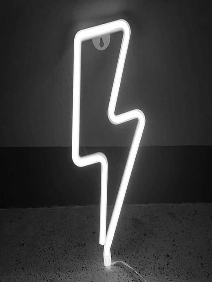 Un letrero de neón blanco en forma de rayo de pie sobre un piso moteado contra una pared oscura. — Rayo de neón Fondos de pantalla
