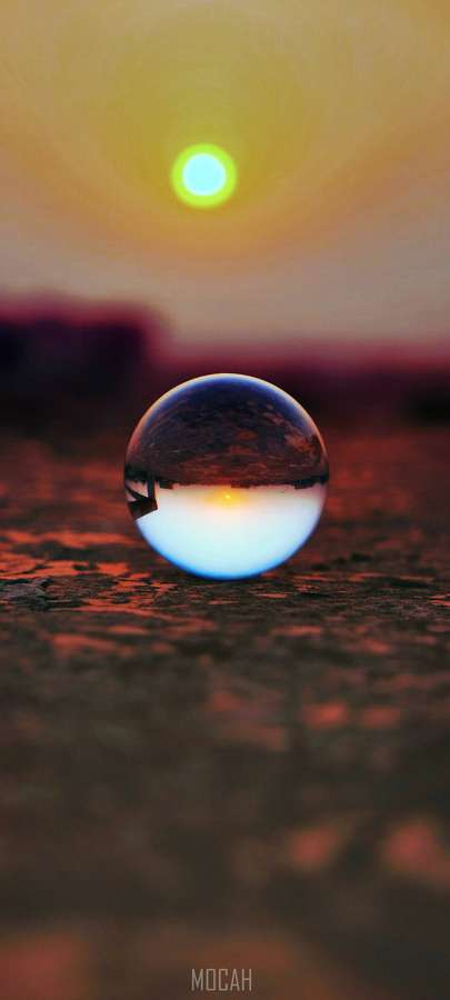 Esfera de vidro refletindo um sol brilhante em solo texturizado ao pôr do sol. — Realme 7 Papéis de Parede