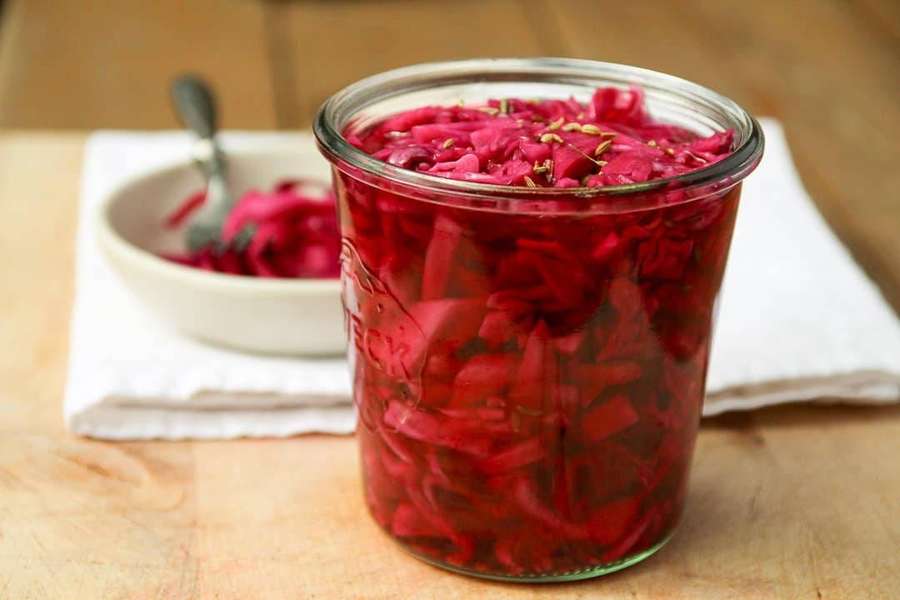 A jar of pickled red cabbage on a wooden table with a small bowl beside it. — Red Cabbage Wallpaper