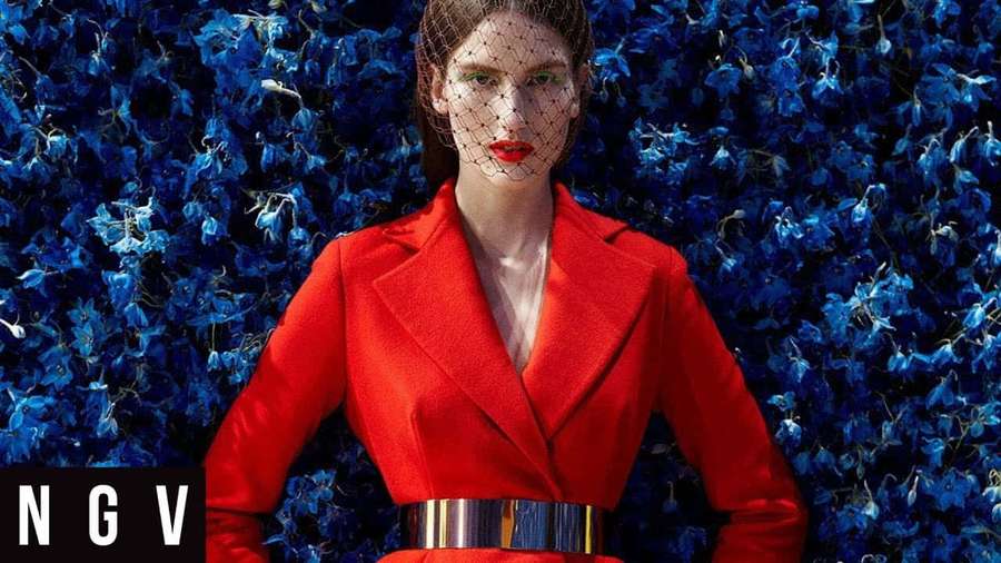 Woman in red blazer and veil standing before blue floral wall. — Red Coat Wallpaper