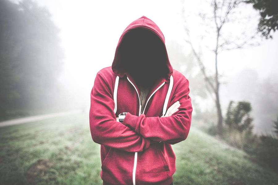 Anonymous figure in red hoodie standing in foggy forest with arms crossed. — Red Hoodie Wallpaper