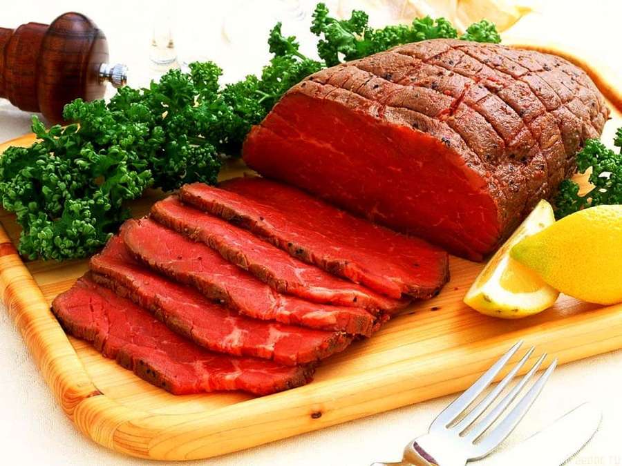 Sliced rare beef with parsley and lemon on wooden board with utensils. — Red Meat Wallpaper