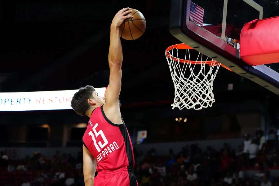 Basketballspiller dunker bolden i en fyldt arena om aftenen. — Reed Sheppard Wallpapers
