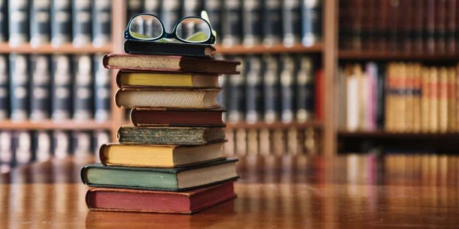 Stack of old books with glasses on top in a library — Reference Picture