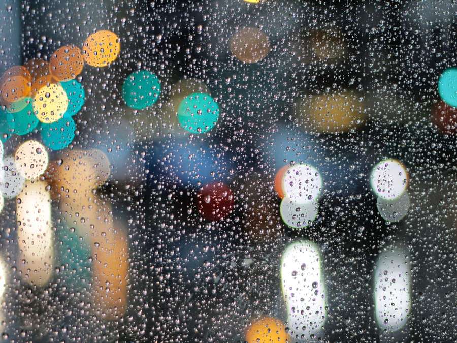 Regentropfen auf Glas mit verschwommenen Stadtlichtern im Hintergrund — Regnerischer Hintergrundbilder Wallpaper