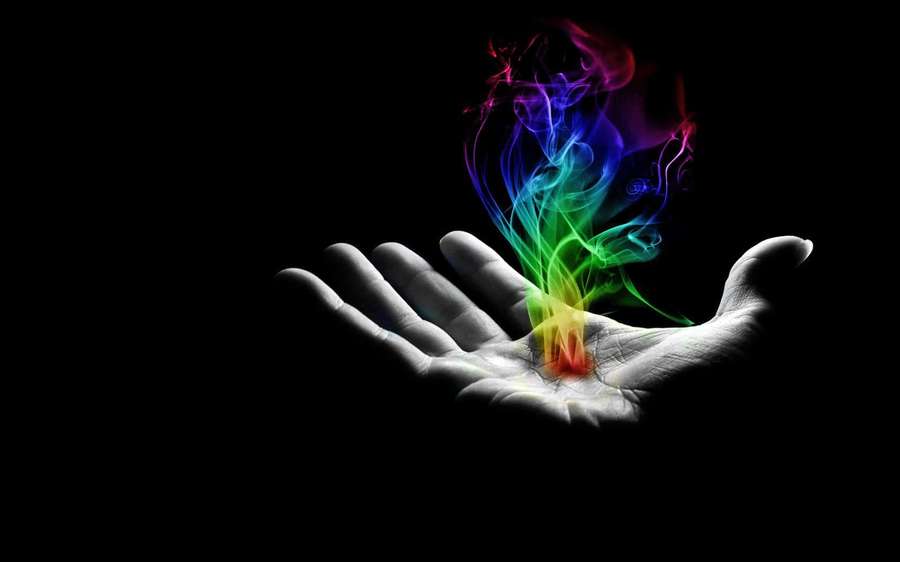 Hand holding colorful glowing smoke against black background — Reiki Wallpaper