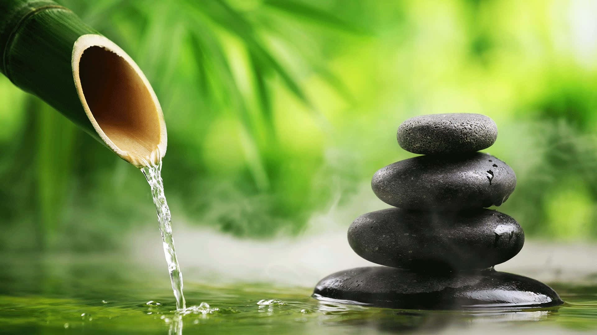 Water pouring from bamboo into pond beside stacked stones with mist — Relaxing Desktop Wallpaper