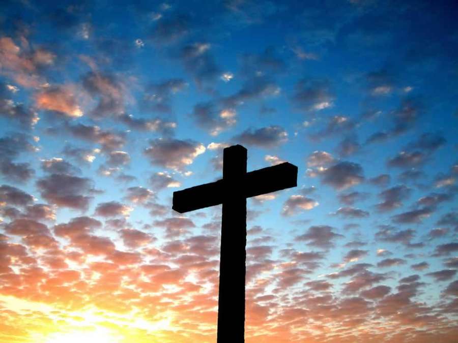 En korssilhuet mod en farverig solopgangshimmel med spredte skyer. — Religious Wallpapers
