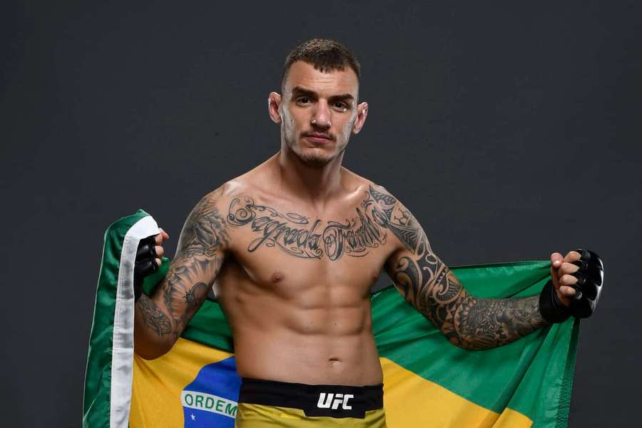A Brazilian MMA fighter with tattoos holds his country's flag in a studio shot. — Renato Moicano Wallpaper