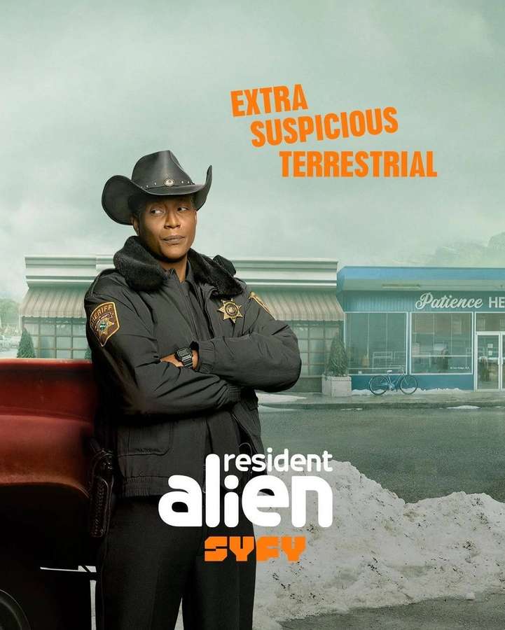 Sheriff in cowboy hat stands by red truck in snowy town with 'Patience' shop and alien show text. — Resident Alien Background