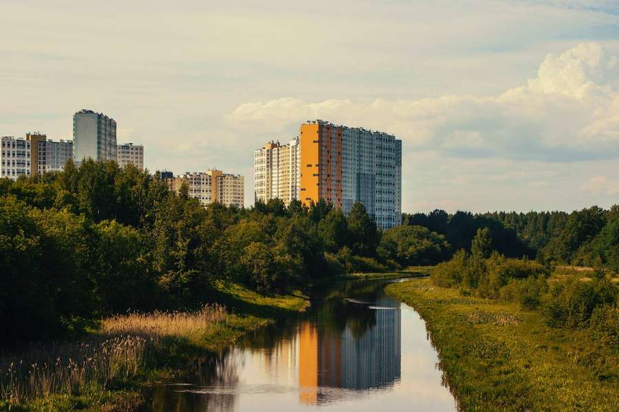 Río con edificios de apartamentos reflejados en el agua rodeados de árboles verdes. — Resolución muy alta Fondos de pantalla