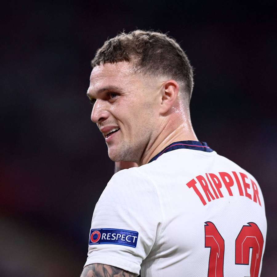 Fußballspieler Trippier in weißem Trikot mit roter Nummer 12 lächelt während eines Nachtspiels. — Respekt Wallpaper