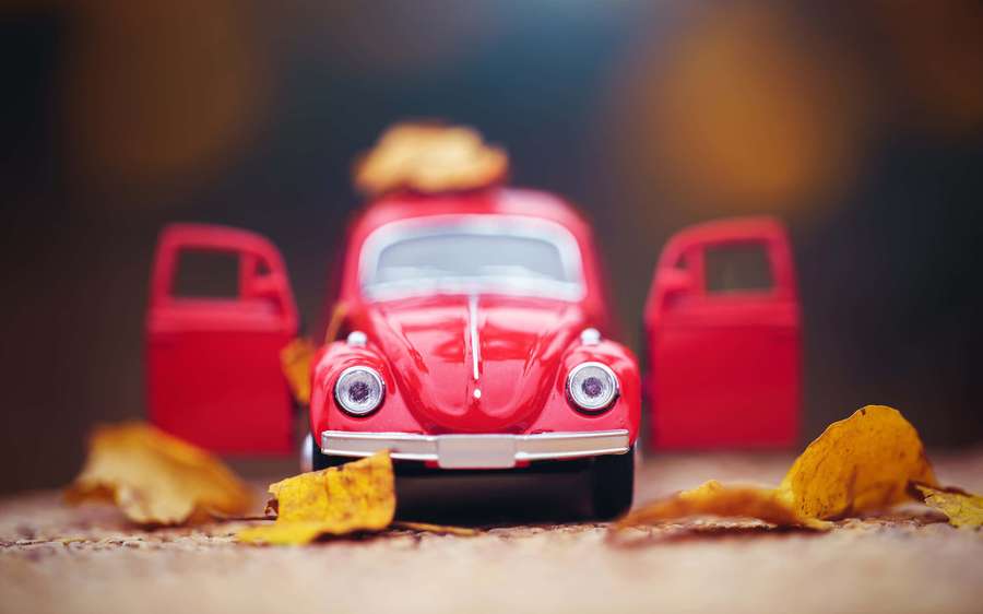 Red vintage toy car surrounded by fallen autumn leaves. — Retro Toys Wallpaper