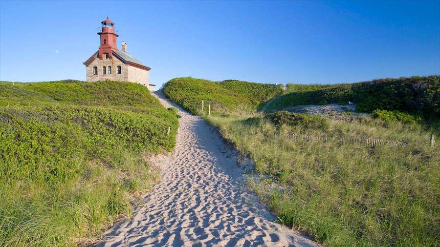 Sandy trail leading to a red lighthouse on grassy dunes under blue sky — Rhode Island Wallpaper