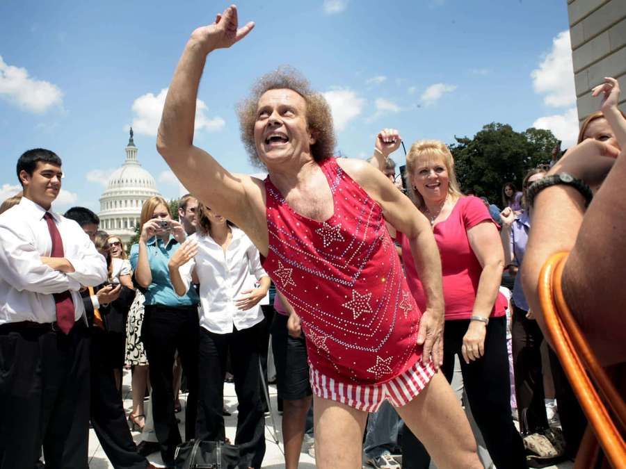 Mann in rotem Paillettenoutfit tanzt vor dem US-Kapitol mit Menschenmenge. — Richard Simmons Wallpaper