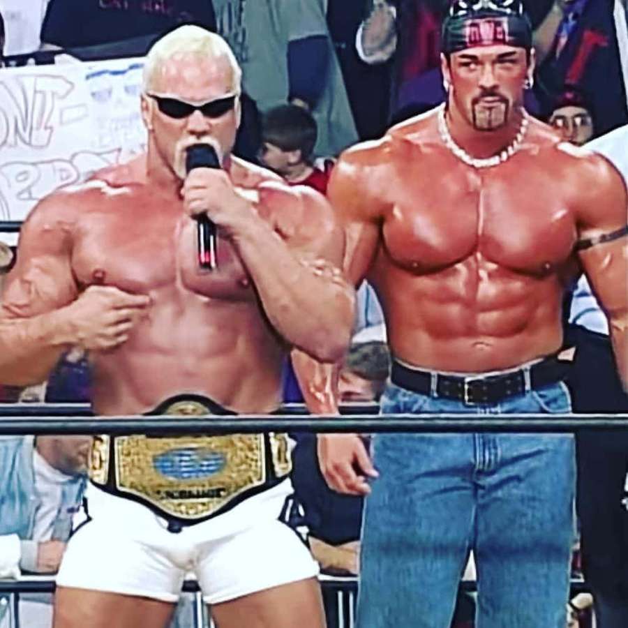 Zwei hemdlose Wrestler im Ring, einer hält ein Mikrofon und trägt einen Meisterschaftsgürtel, der andere in Jeans. — Ringen Wallpaper