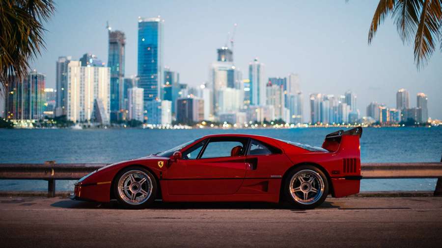 Roter Ferrari F40 am Wasser geparkt mit Stadtsilhouette in der Dämmerung. — River View Bilder