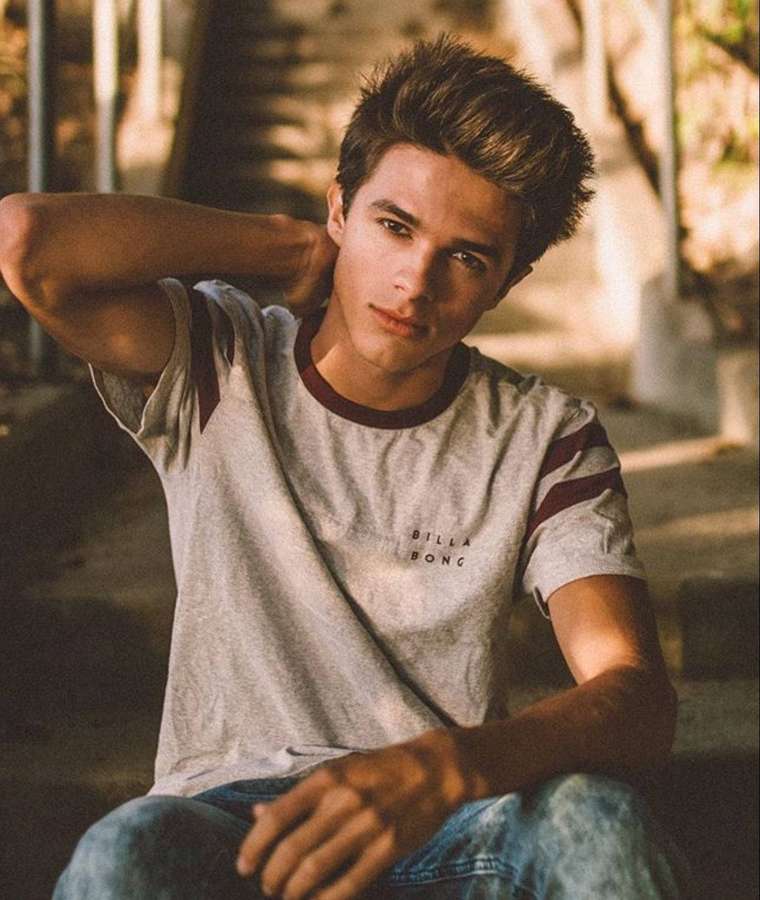 Young man in grey tshirt and jeans sitting on steps in golden sunlight — Rivera Background