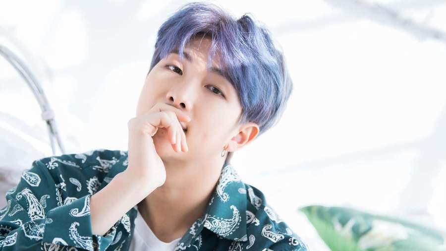 Young man with blue hair in green paisley shirt posing thoughtfully. — Rm Background