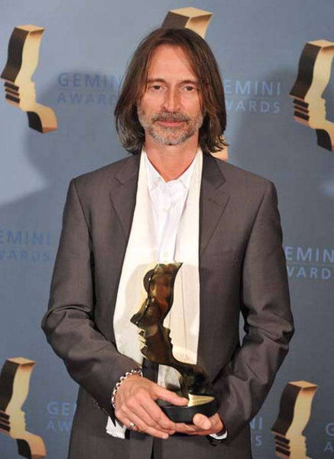 Man in suit holding Gemini Award statue at event. — Robert Carlyle Background