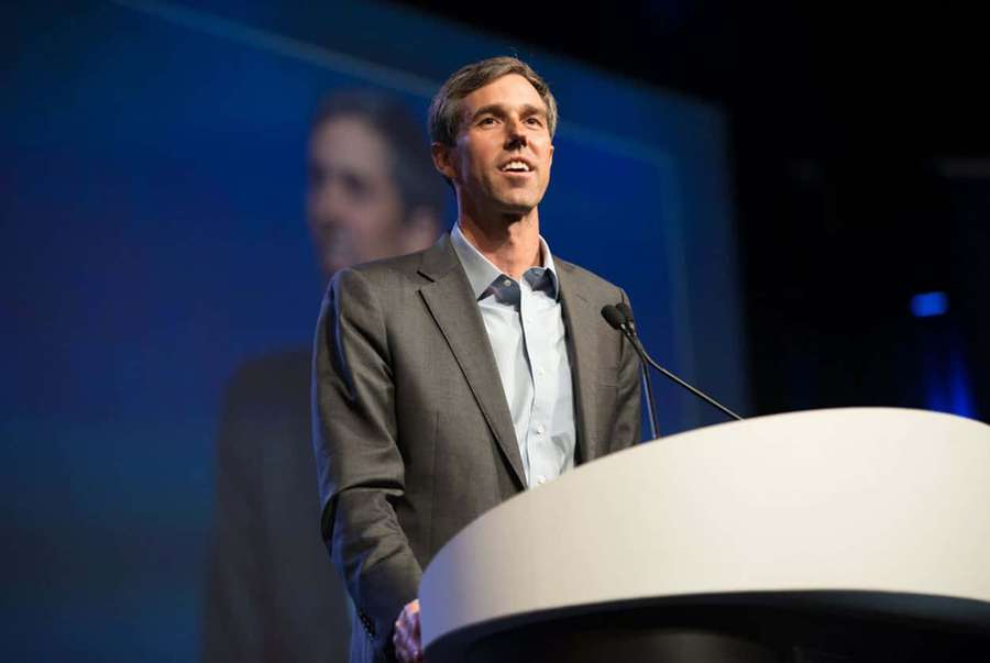 Man giving a speech at a podium under blue stage lights. — Robert O'rourke Wallpaper