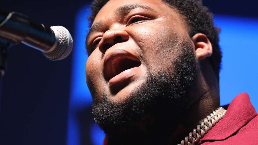 Singer performing on stage with microphone and gold chain. — Rod Background