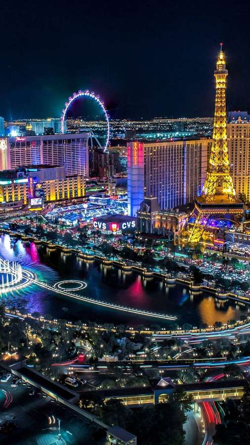 Horizonte vibrante de Las Vegas à noite com marcos iluminados e reflexos na água. — Roda gigante Papéis de Parede