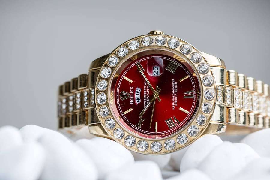 Eine goldene Rolex-Uhr mit Diamantlünette und rotem Zifferblatt auf weißem Samt. — Rolex HD Wallpaper