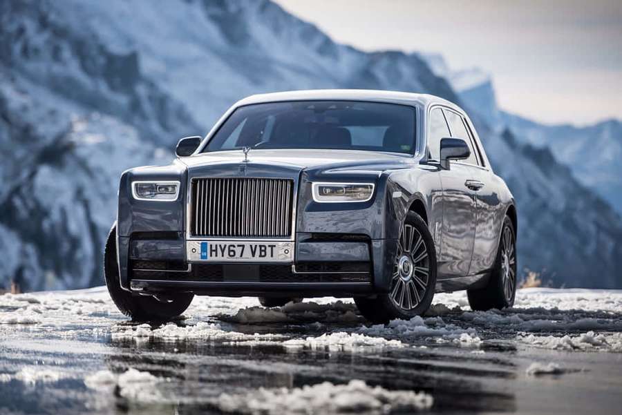 Luxury silver Rolls Royce on snowy mountain road with icy reflections. — Rolls Royce Phantom Wallpaper