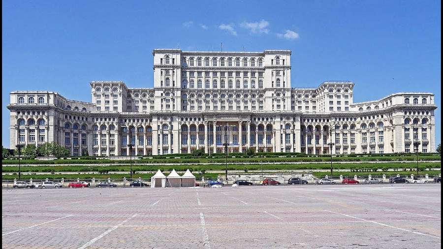 Suuri hallintorakennus, jossa on klassinen arkkitehtuuri ja kivetty aukio edessä. — Romania Taustakuvat