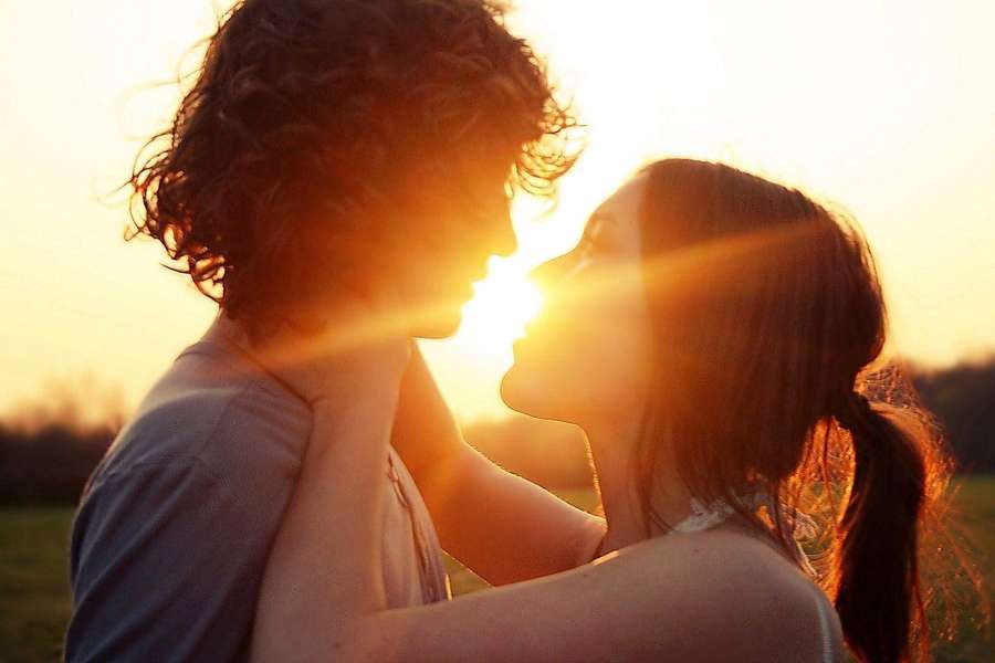 A couple embracing in silhouette against a golden sunset. — Romantic Couples Wallpaper