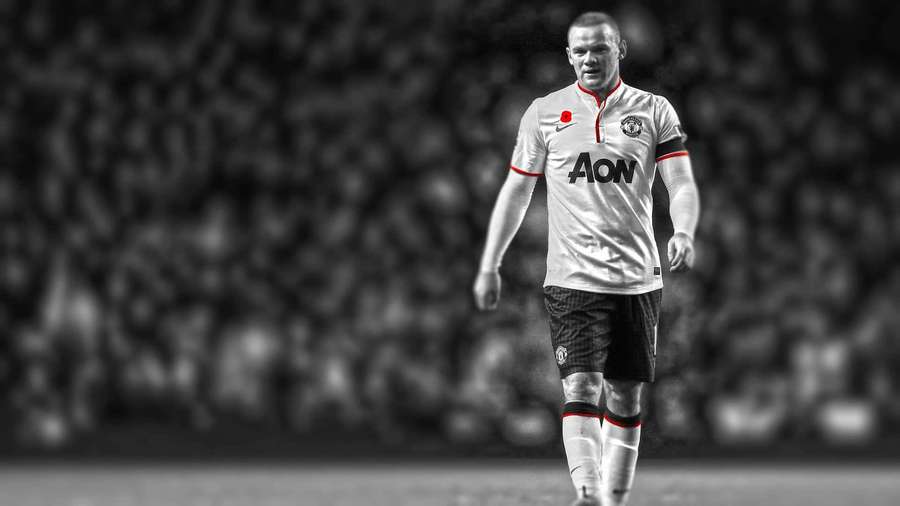 Fußballspieler in weißem Trikot geht auf dem Feld mit verschwommener Menschenmenge. — Rooney Bilder