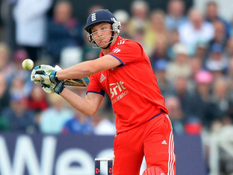 Cricket player in red uniform swinging bat during daytime match. — Root Wallpaper