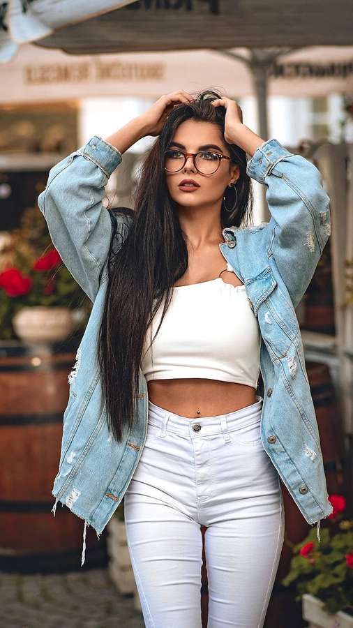 Una mujer elegante en chaqueta de mezclilla y atuendo blanco posando al aire libre en un café. — Ropa Fondos de pantalla