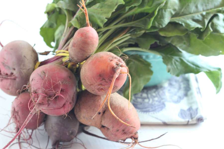 Frische Rüben mit grünen Spitzen auf einer weißen Oberfläche mit gemustertem Tuch. — Rote Beete Wallpaper