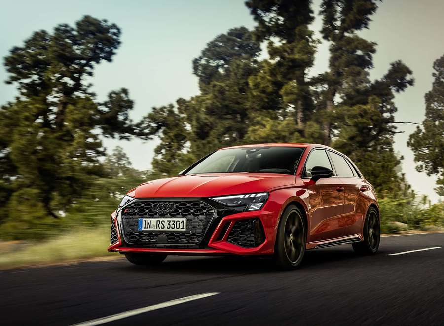 Red Audi RS3 speeding through a forested road with blurred green trees. — Rs Background