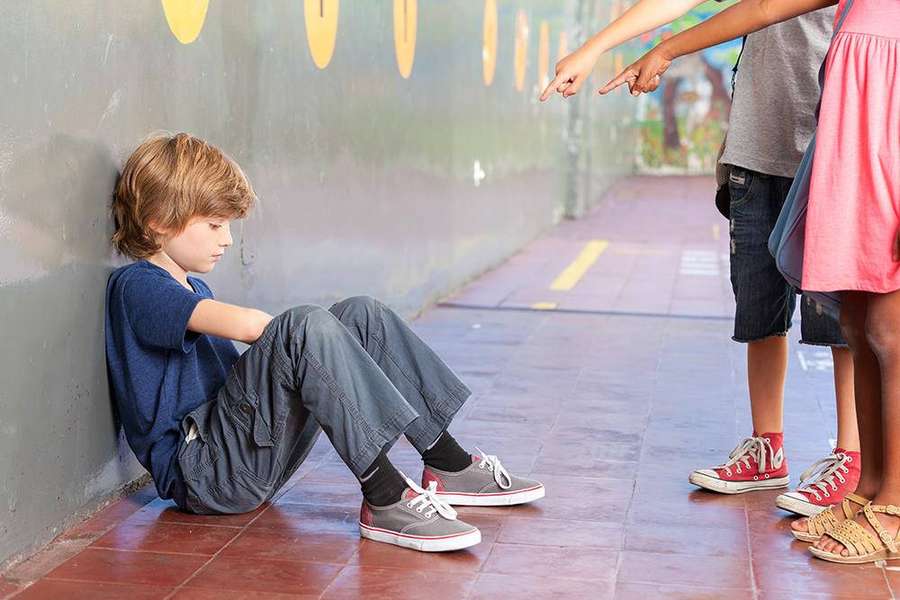 Un niño sentado en el suelo mientras otros lo señalan. — Rudo Fondos de pantalla