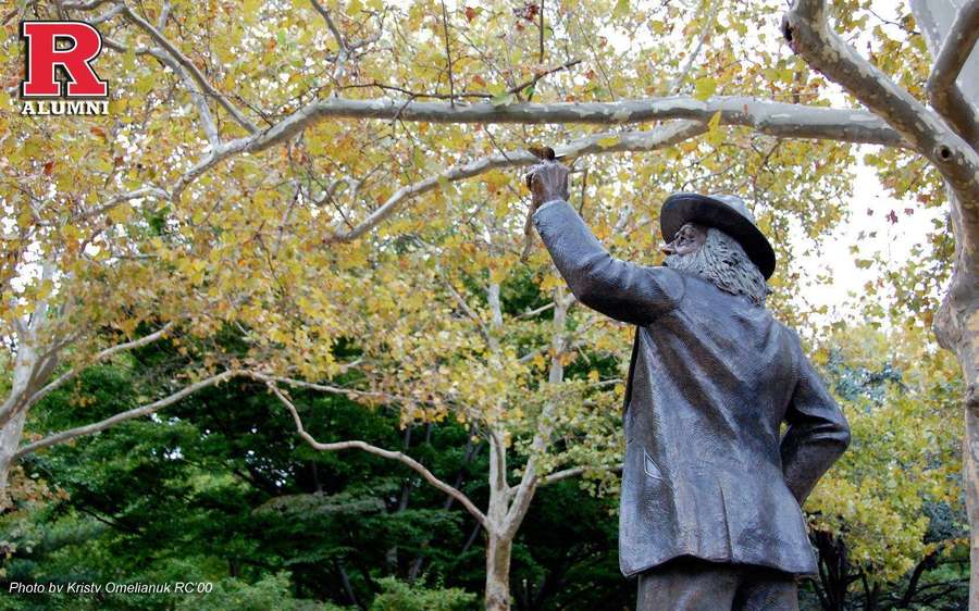 Bronzestatue eines Mannes mit Hut, der nach Herbstblättern an Bäumen greift. — Rutgers Bilder