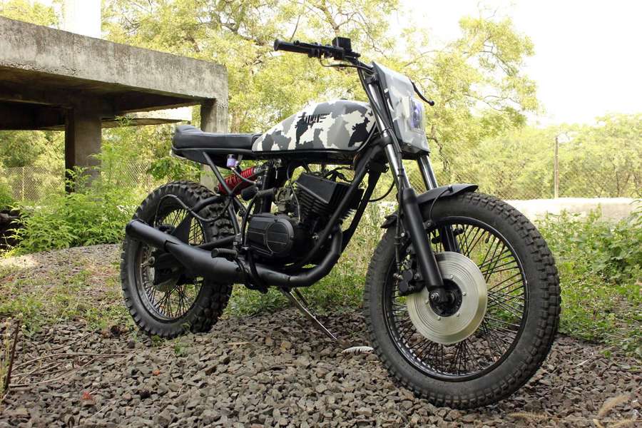 Custom camo motorcycle parked on gravel under a concrete overpass. — Rx100 Wallpaper