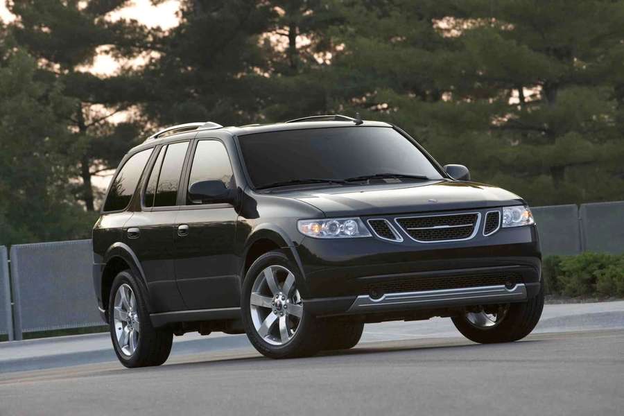Black Saab 9-7x SUV driving on road with trees and fence at sunset. — Saab 9-4x Wallpaper