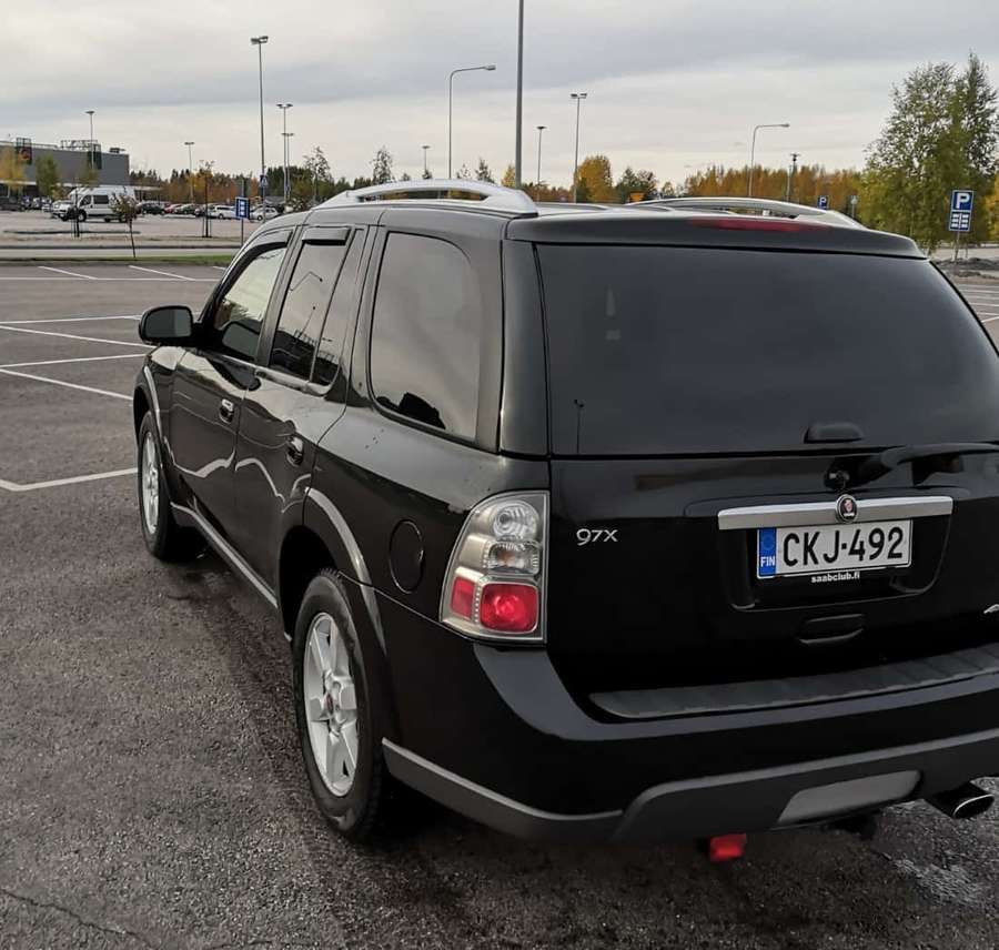 Black Saab 97x SUV parked in a parking lot with autumn trees and overcast sky. — Saab 9-5 Wallpaper
