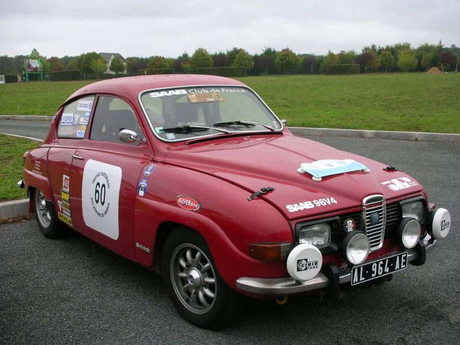 Vintage red Saab rally car with number 60 parked on asphalt near grassy field. — Saab 96 Wallpaper