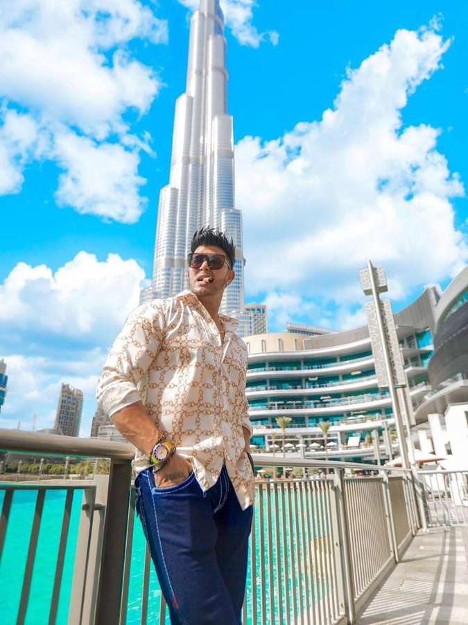Mann mit Sonnenbrille posiert am Wasser mit Burj Khalifa im Hintergrund. — Sahil Khan Wallpaper
