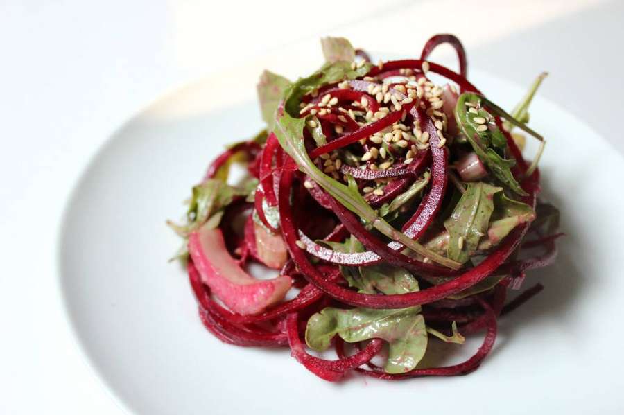 Ein farbenfroher Rote-Bete-Salat mit Sesamkörnern und Grünzeug auf einem weißen Teller. — Salat Wallpaper