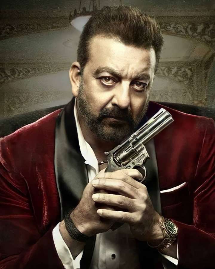 Mann in rotem Samtanzug hält silbernen Revolver mit intensivem Blick in verziertem Raum. — Sanjay Dutt Bilder