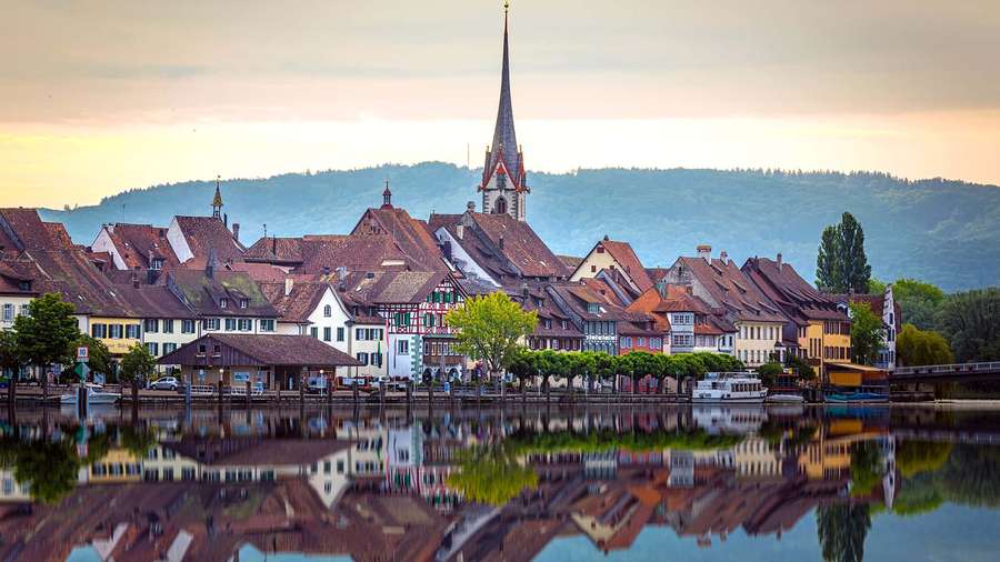 Historic town with church spire reflected in water during sunset. — Schaffhausen Wallpaper