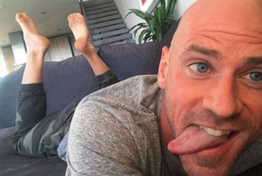 Mann streckt Zunge heraus während er barfuß auf Couch lümmelt — Schauspieler Wallpaper