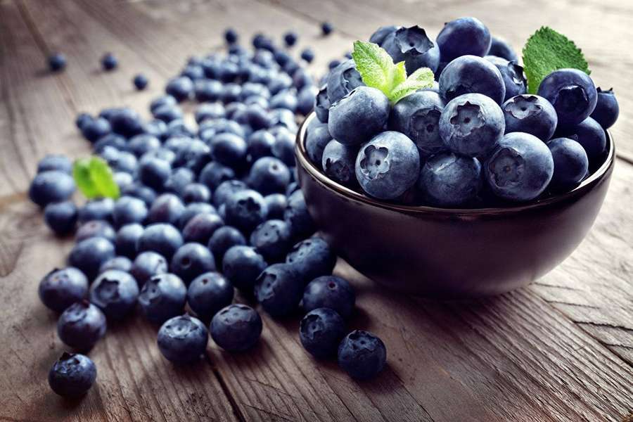 Eine Schale mit frischen Blaubeeren und Minzblättern auf einer Holzoberfläche. — Schüsseln Wallpaper
